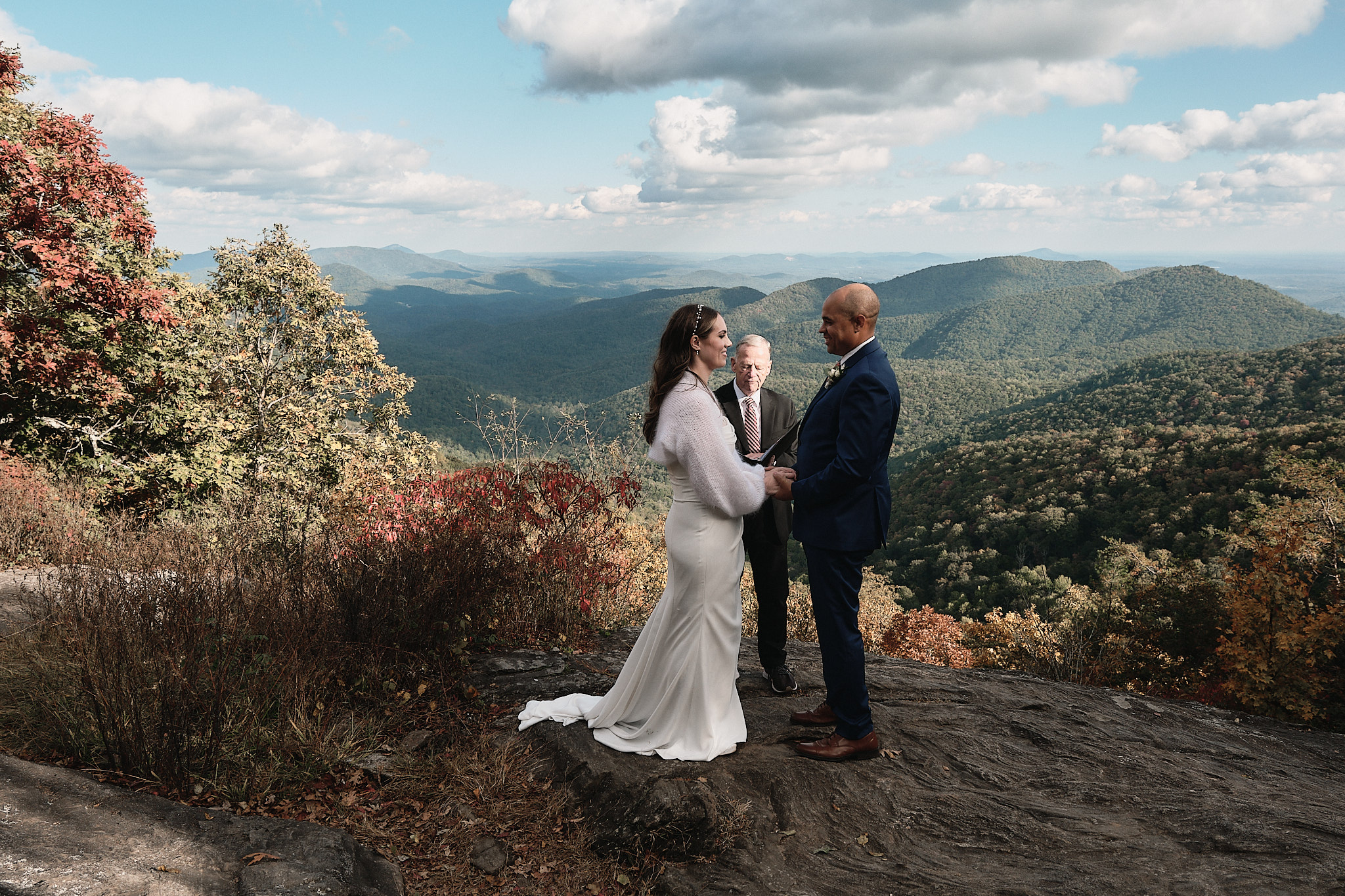 Couple eloping on a mountaintop with officiant and just the two of them