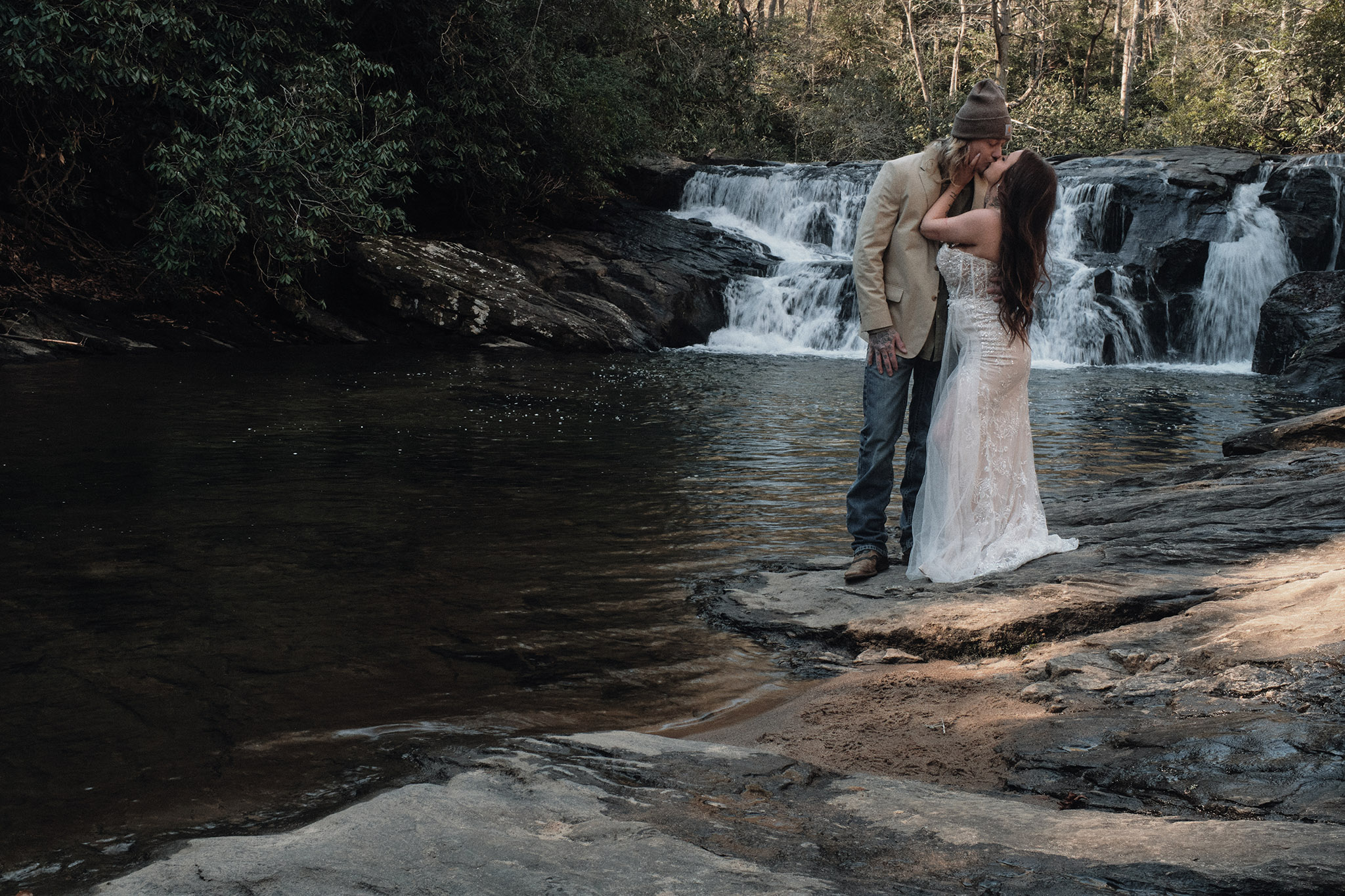 Eloping couple kissing in front of a waterfall