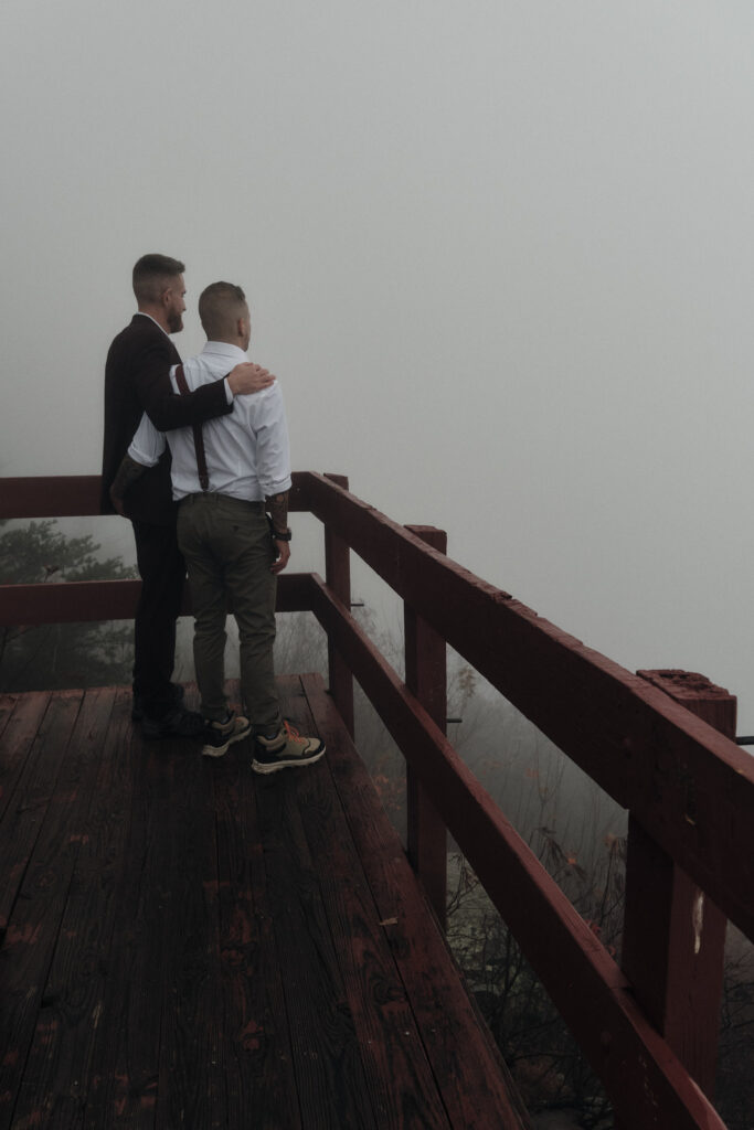 Eloping couple looking out on a foggy mountain scene