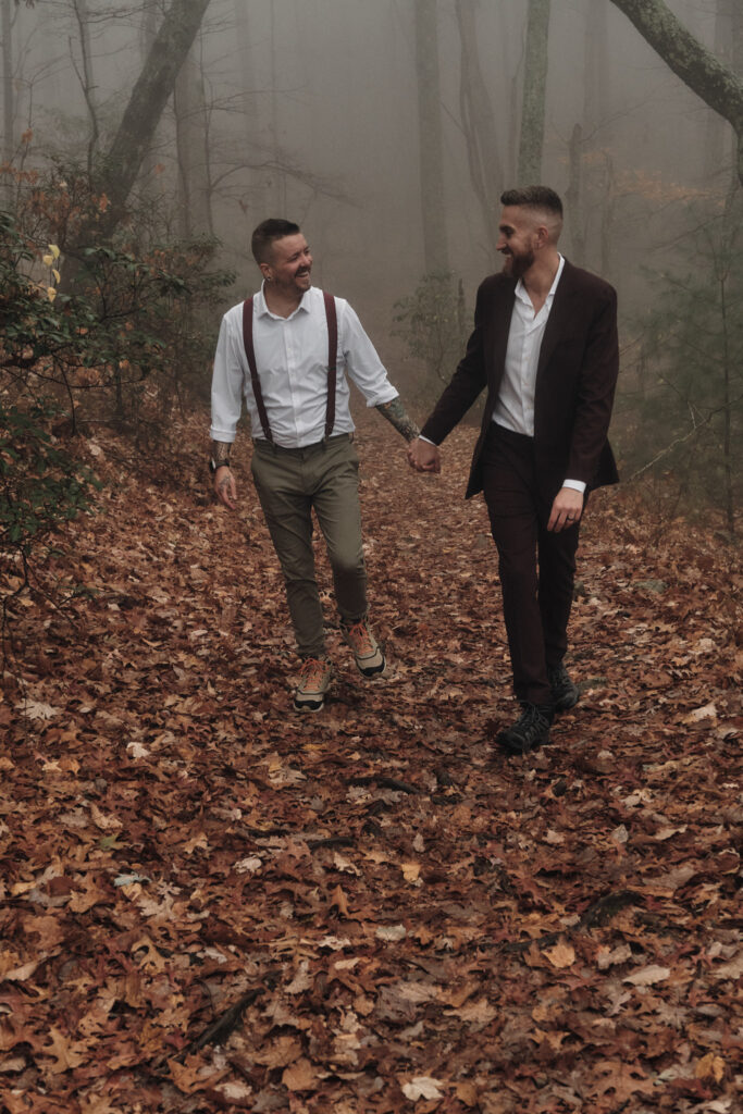 Couple laughing and walking in autumn leaves during an elopement