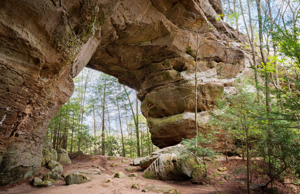 Natural rocky arch over a trail in the woods.