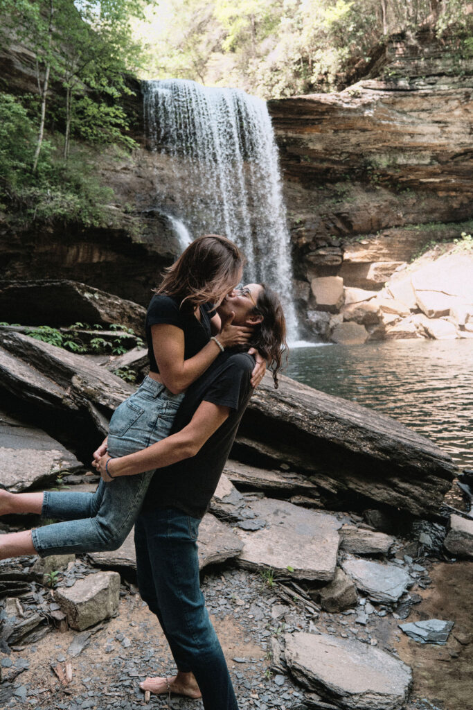 LGBTQ couple kissing in front of a waterfall.