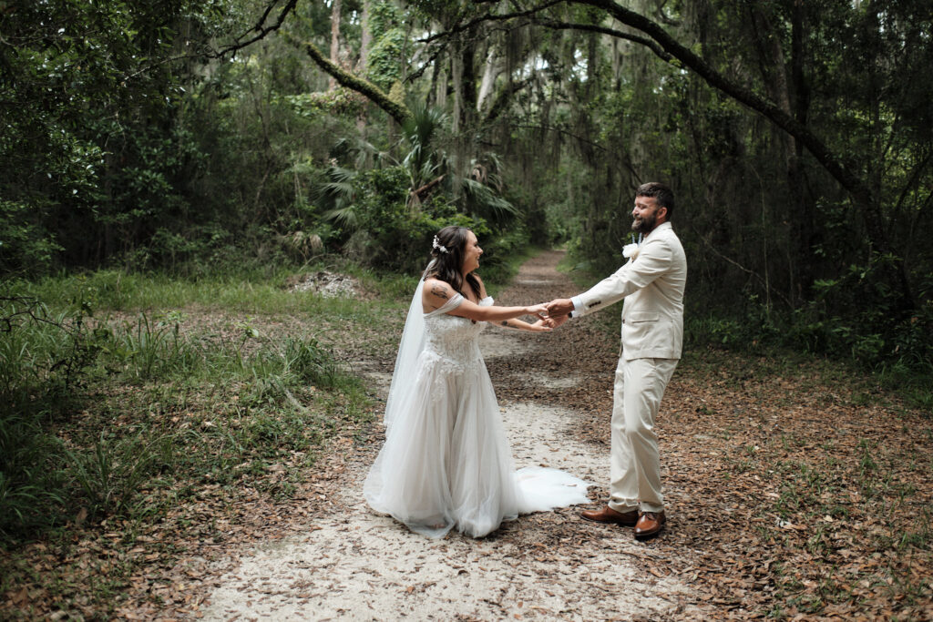 Eloping couple enjoys spinning each other around in the middle of Spanish moss covered trees