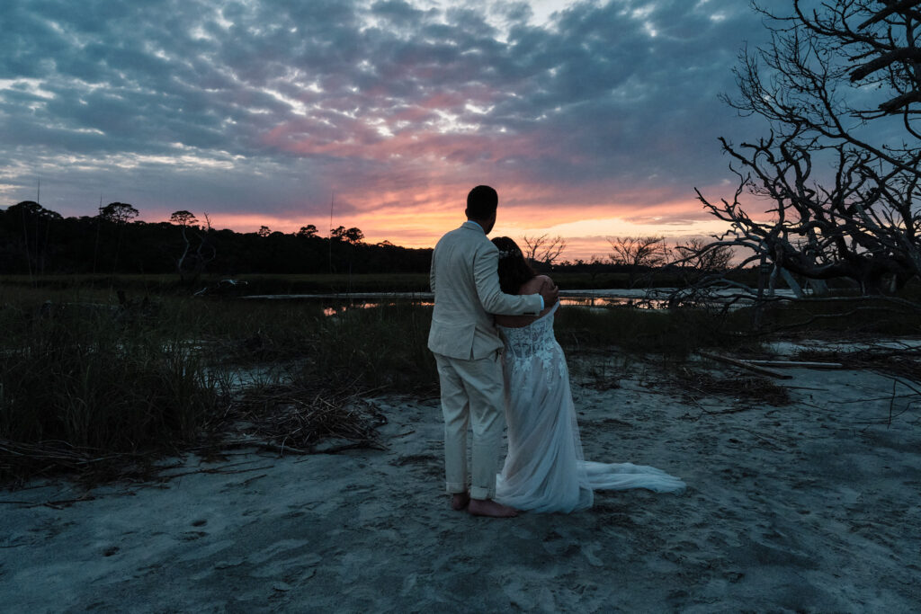 Couple looks at a colorful sunset at the end of the Jekyll Island Wedding