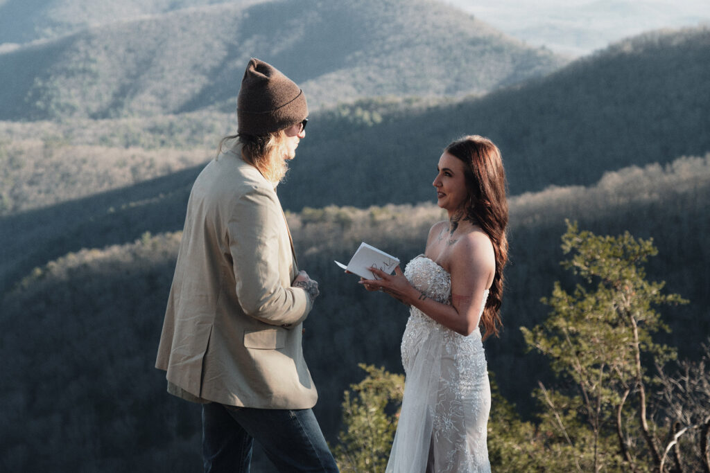 Couple reading their own vows on their elopement day atop the mountains