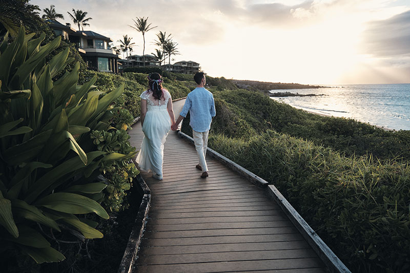 Eloping couple walks along a boardwalk in Hawaii