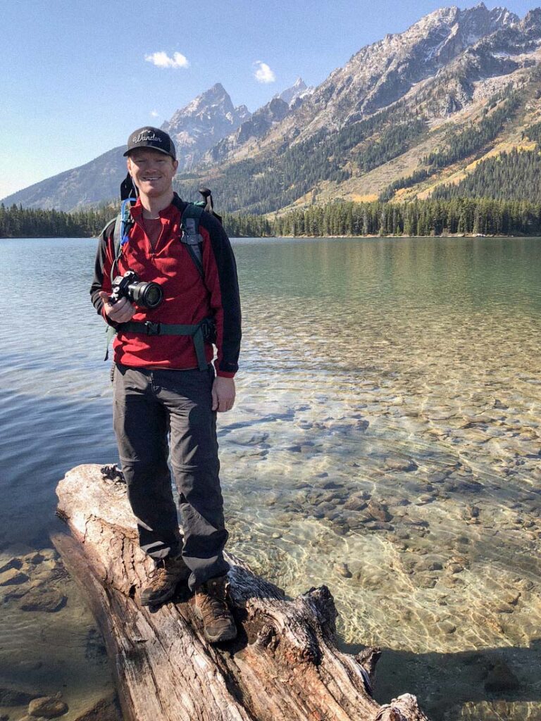 Elopement photographer holds a camera with mountains in the background