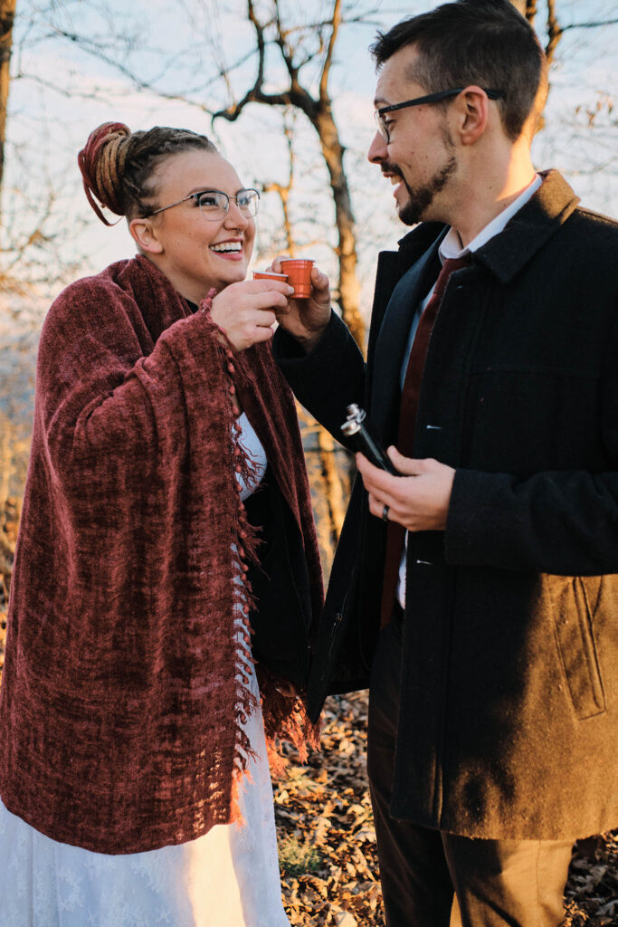 Eloping couple sharing a shot of liquor at the top of the mountain