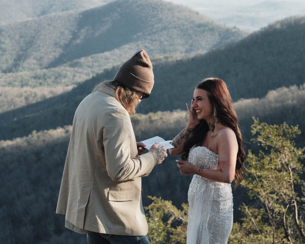 Hiking eloping couple reading their own vows and laughing