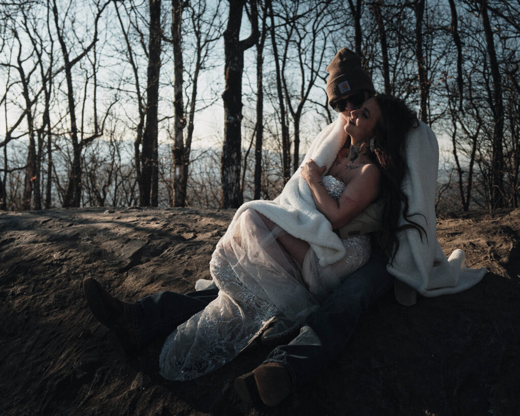 Eloping couple snuggling on top of the mountain